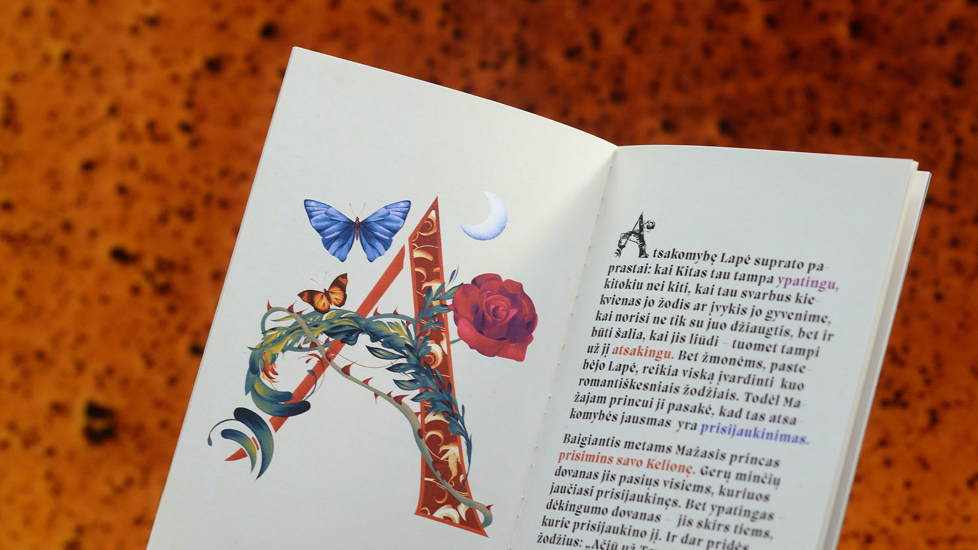 “Dėkingumo Kalėdos” catalogue spread with illustrated letter A and fairy-tale motifs